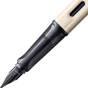 Puede incluir: Una pluma estilogr&aacute;fica negra y blanca con un cartucho de tinta transparente y una tapa beige. La pluma tiene una punta de metal con la etiqueta "LAMY M".