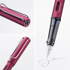 May include: A rose gold fountain pen with a clear ink cartridge and a metal clip. The pen is writing on a white surface with blue ink.