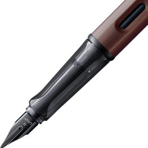 Pode incluir: Uma caneta-tinteiro Lamy Safari marrom e preta com uma pena m&eacute;dia. A caneta tem um cartucho de tinta transparente e uma tampa preta.