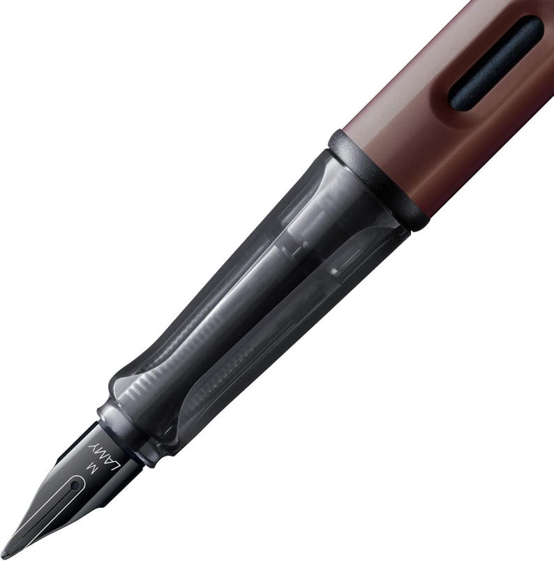 Pode incluir: Uma caneta-tinteiro Lamy Safari marrom e preta com uma pena m&eacute;dia. A caneta tem um cartucho de tinta transparente e uma tampa preta.