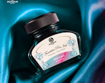 May include: A 30 ml bottle of turquoise fountain pen ink with a pink sheen. The bottle has a label that says "Octopus Fluids Fountain Pen Ink Turquoise Pink Sheen Mermaid".