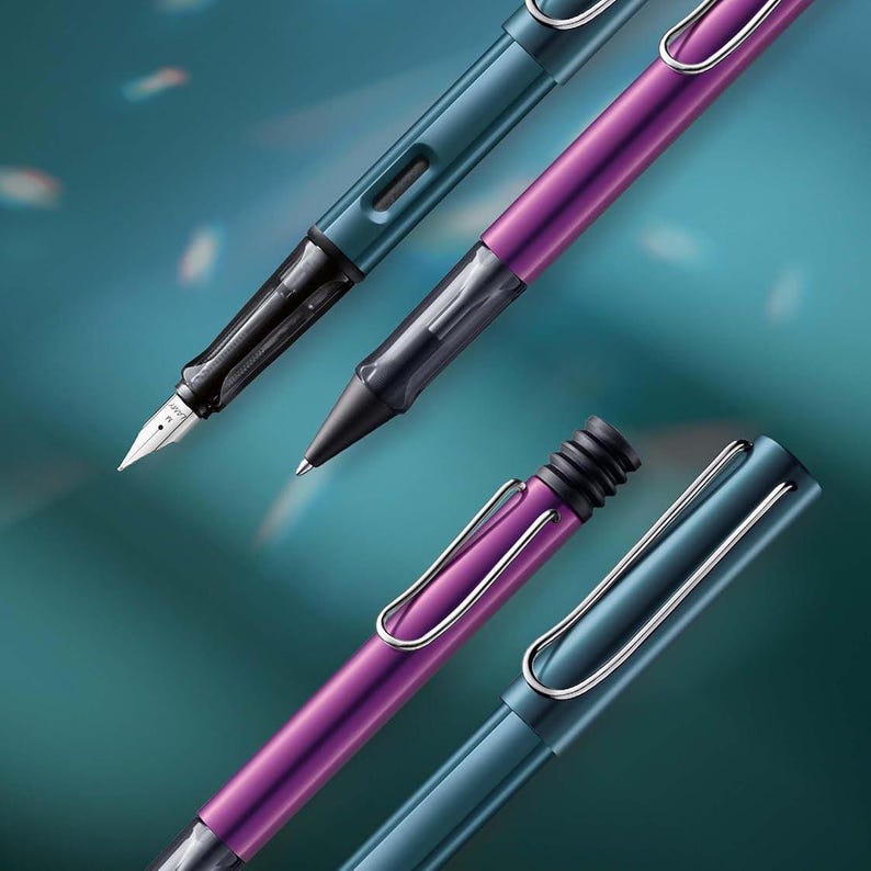 May include: Three pens in different colours: teal, purple, and a darker shade of teal. The pens have a unique clip design and are made of metal.