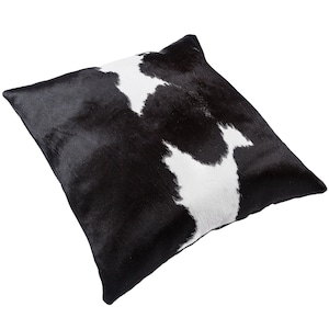 May include: Black and white cowhide throw pillow with a soft, plush texture. The pillow is rectangular and has a subtle sheen.