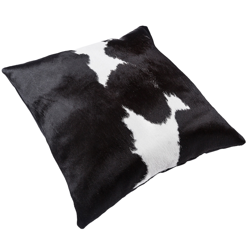 May include: Black and white cowhide throw pillow with a soft, plush texture. The pillow is rectangular and has a subtle sheen.