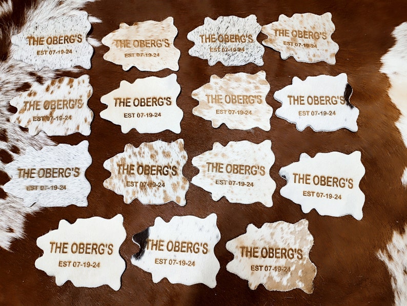 May include: Twelve cowhide rugs with the text "THE OBERG'S EST 07-19-24" embossed in gold lettering.