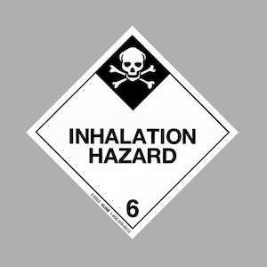 Könnte beinhalten: Ein schwarz-weißes, rautenförmiges Warnschild mit Totenkopf und Knochen und dem Text "Inhalation Hazard". Das Schild hat einen schwarzen Rand und die Nummer "6" in der rechten unteren Ecke.