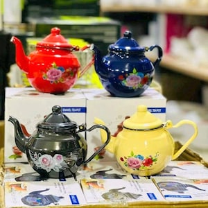 May include: Four enamel teapots in red, dark blue, black, and yellow, each featuring a floral rose pattern, a curved spout, a handle, and a lid. The teapots are displayed on top of their individual white product boxes with printed labels.