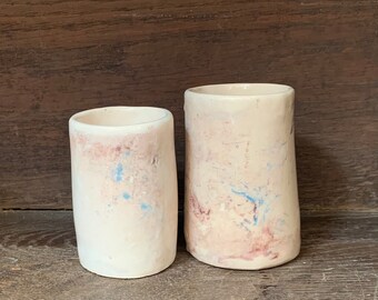 Mugs  ou petits vases aux formes organiques en faïence faits à la main. Décor aux couleurs douces qui se fondent dans le fond.