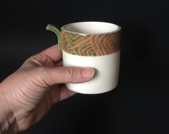 Tasse originale au décor géométrique  avec l'anse qui reprends la forme du motif.