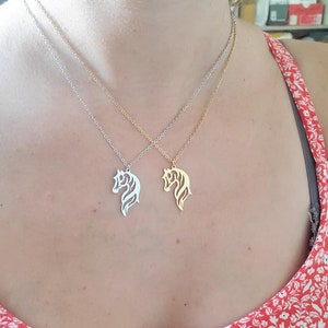 May include: Two silver necklaces with horse head pendants. One necklace has a gold horse head pendant and the other has a silver horse head pendant.
