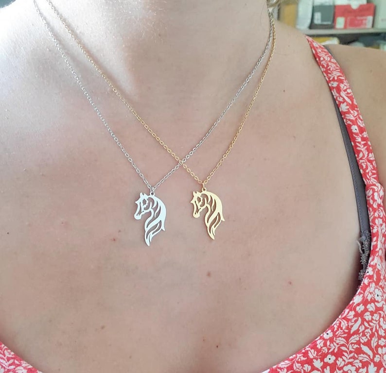 May include: Two silver necklaces with horse head pendants. One necklace has a gold horse head pendant and the other has a silver horse head pendant.