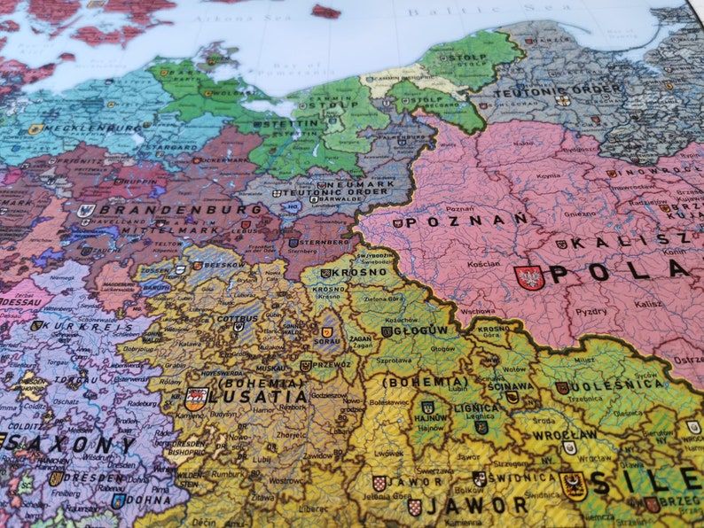 May include: A vintage map of Europe with detailed borders and city names. The map is printed on paper and has a worn, aged look. The map is in shades of brown, green, pink, and blue.
