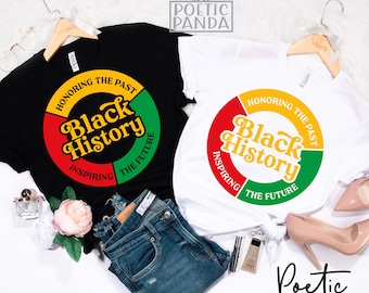 May include: Two t-shirts with a circular design featuring the words "Honoring the Past", "Black History", "Inspiring", and "The Future". The design is in red, yellow, and green. The t-shirts are on a white background with a pair of jeans and other accessories.