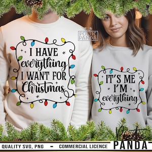 Può includere: Due felpe bianche con testo a tema natalizio. Una dice "I HAVE everything I WANT FOR Christmas" e l'altra "IT'S ME I'M everything". Entrambi i design sono incorniciati da luci natalizie colorate.