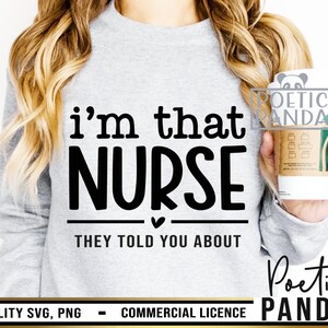 K&ouml;nnte beinhalten: Ein graues Sweatshirt mit dem Text "i'm that NURSE THEY TOLD YOU ABOUT" auf der Vorderseite. Das Sweatshirt wird von einer Person getragen, die eine Kaffeetasse h&auml;lt.