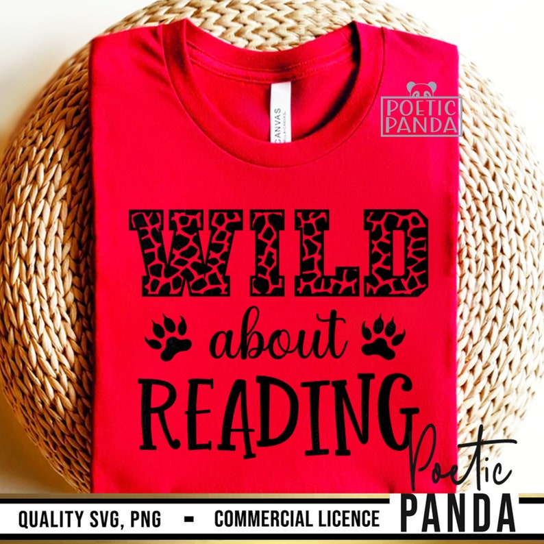 Puede incluir: Una camiseta roja con las palabras "WILD about READING" en negro. La palabra "WILD" tiene un estampado de jirafa. Huellas de patas est&aacute;n a ambos lados de la palabra "about". La camiseta est&aacute; sobre una superficie tejida de color marr&oacute;n claro.