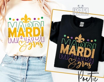 May include: Two t-shirts with a Mardi Gras design. The design features the words "Mardi Gras" in gold glitter letters with purple and green accents. The shirts are white and black.