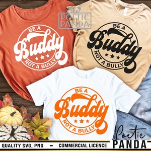 以下が含まれることがあります： レトロなフォントで「Be a Buddy Not a Bully」と書かれたTシャツが3枚。シャツはオレンジ、白、ベージュ。オレンジのシャツは白文字、ベージュのシャツは黒文字、白いシャツはオレンジ文字です。
