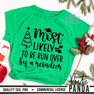 May include: A bright green t-shirt with the text "Most Likely To Be Run Over by a Reindeer" in black. The design includes a Christmas tree, Santa hat, and holly. The shirt is a short-sleeved crew neck.
