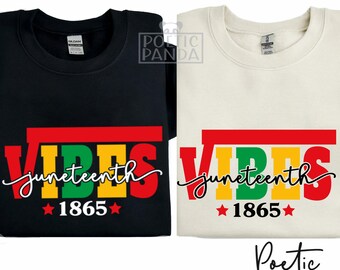 May include: Two t-shirts with a graphic design that says "Vibes Juneteenth 1865" in red, yellow, green, and black. The text is in a bold, blocky font. The t-shirts are on a white background.