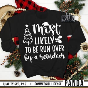 May include: Black sweatshirt with the text "Most Likely To Be Run Over by a Reindeer" in white. The design includes a Christmas tree, Santa hat, and holly. The sweatshirt is surrounded by Christmas decorations.