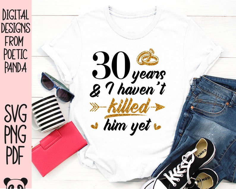 May include: White t-shirt with gold glitter text that reads "30 years & I haven't killed him yet". The text is surrounded by a gold glitter arrow and two gold glitter rings.