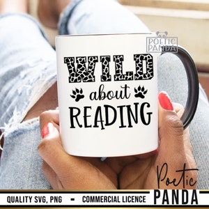 Puede incluir: Taza de cer&aacute;mica blanca con asa y borde negros, con el texto "WILD about READING" en negro. La palabra "WILD" tiene un estampado de jirafa. Las huellas de patas se utilizan como elementos de dise&ntilde;o. La taza est&aacute; sujeta por una persona.