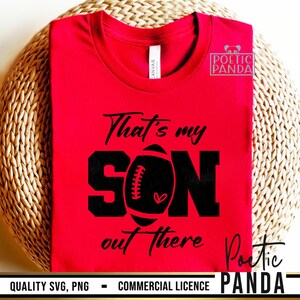 May include: Red t-shirt with black text that reads "That's my SON out there" with a football graphic in the middle of the word "SON".