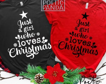 Puede incluir: Una camiseta negra y una camiseta roja, cada una con un gráfico en forma de árbol de Navidad formado por el texto Just a girl who loves Christmas, decorado con hojas de acebo, bayas y copos de nieve, rematado con una estrella.