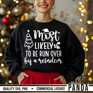 May include: Black sweatshirt with the text "Most Likely To Be Run Over by a Reindeer" in white. The design includes a Christmas tree, Santa hat, and holly. The sweatshirt has a red band at the waist.