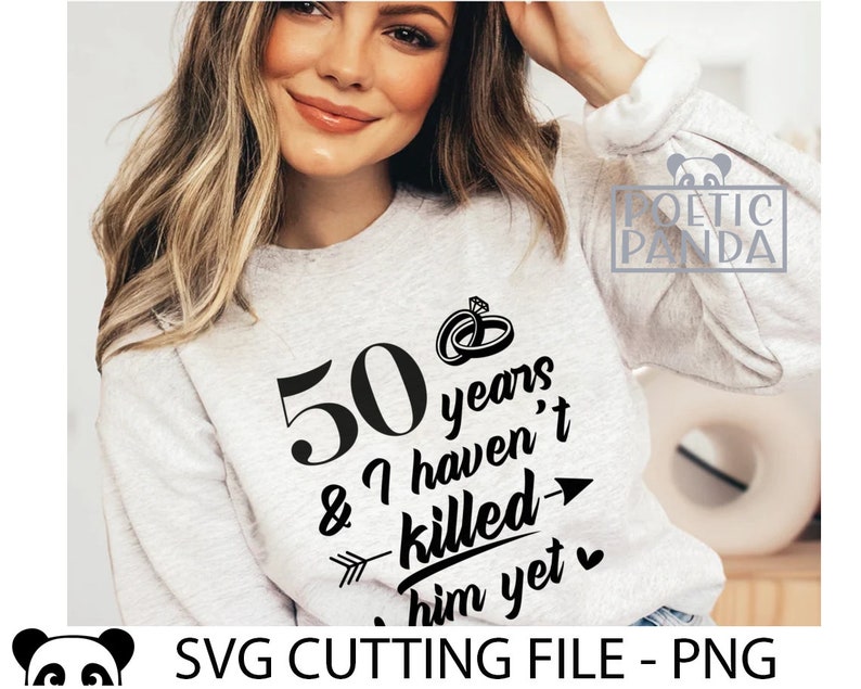 May include: A white sweatshirt with black text that reads "50 years & I haven't killed him yet" with a heart and arrow graphic. The text is in a handwritten font.