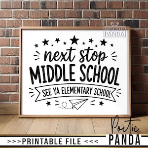 以下が含まれることがあります： 「next stop MIDDLE SCHOOL」の黒い文字と星、紙飛行機のデザインが施された額入りのプリント。 「SEE YA ELEMENTARY SCHOOL」のフレーズも含まれています。 フレームはライトブラウンで、背景は白です。