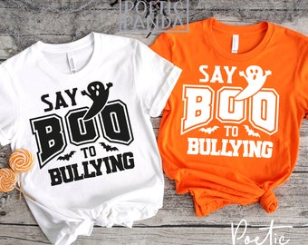Peut inclure: Deux t-shirts sur le thème d'Halloween. Un t-shirt blanc et un t-shirt orange présentent tous les deux un fantôme et le texte "Say Boo to Bullying".