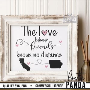 May include: A white framed print with the text "The love between friends knows no distance" and two black silhouettes of states connected by a dotted line. The print has a pink heart and pink hearts along the dotted line.