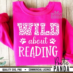 Puede incluir: Una sudadera rosa brillante con las palabras "WILD about READING" en blanco. La palabra "WILD" tiene un patr&oacute;n de jirafa. Huellas de patas est&aacute;n debajo. La sudadera tiene el texto "QUALITY SVG, PNG - COMMERCIAL LICENCE" en la parte inferior.