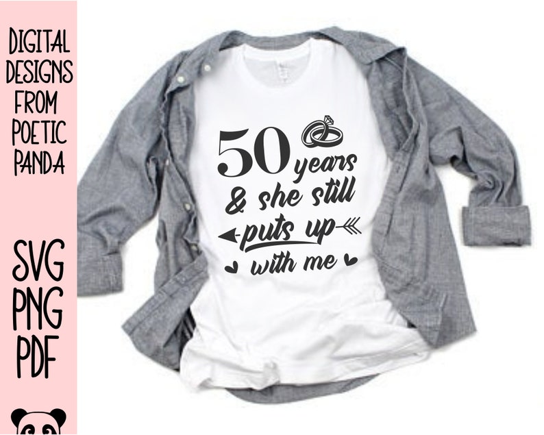 May include: White t-shirt with black text that reads "50 years & she still puts up with me" and a small drawing of two wedding rings.