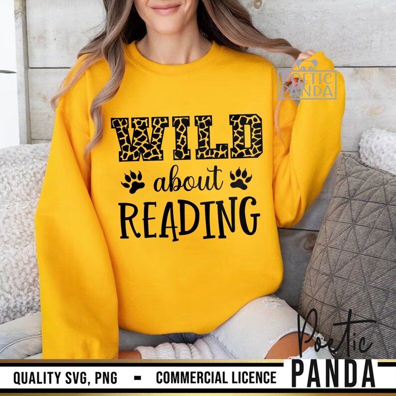 Puede incluir: Sudadera amarilla mostaza con el texto negro "WILD about READING". La palabra "WILD" tiene un estampado de jirafa. Huellas de patas a ambos lados de la palabra "about". La sudadera es de cuello redondo y manga larga.