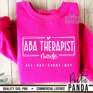 May include: Pink sweatshirt with white text that reads "ABA Therapist mode ALL DAY EVERY DAY" and a small heart above the text. The text is framed in a double white border. The sweatshirt has the words "Poetic Panda" in white text on the bottom right corner.