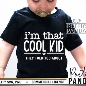 以下が含まれることがあります： 「i'm that COOL KID THEY TOLD YOU ABOUT」と白文字で書かれた黒いTシャツ。 「told you about」の言葉の上に小さな白いハートがある。