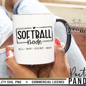 May include: White ceramic mug with a black handle featuring the text "SOFTBALL mode ALL DAY EVERY DAY" in a black font. The mug is held by a person with red nail polish.
