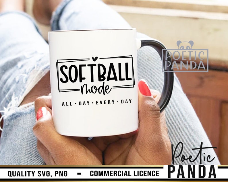 May include: White ceramic mug with a black handle featuring the text "SOFTBALL mode ALL DAY EVERY DAY" in a black font. The mug is held by a person with red nail polish.