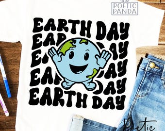 May include: White t-shirt featuring a cartoon Earth with a smiling face and outstretched arms. The words "EARTH DAY" are printed in a repeating pattern around the Earth graphic. The shirt is paired with blue jeans.