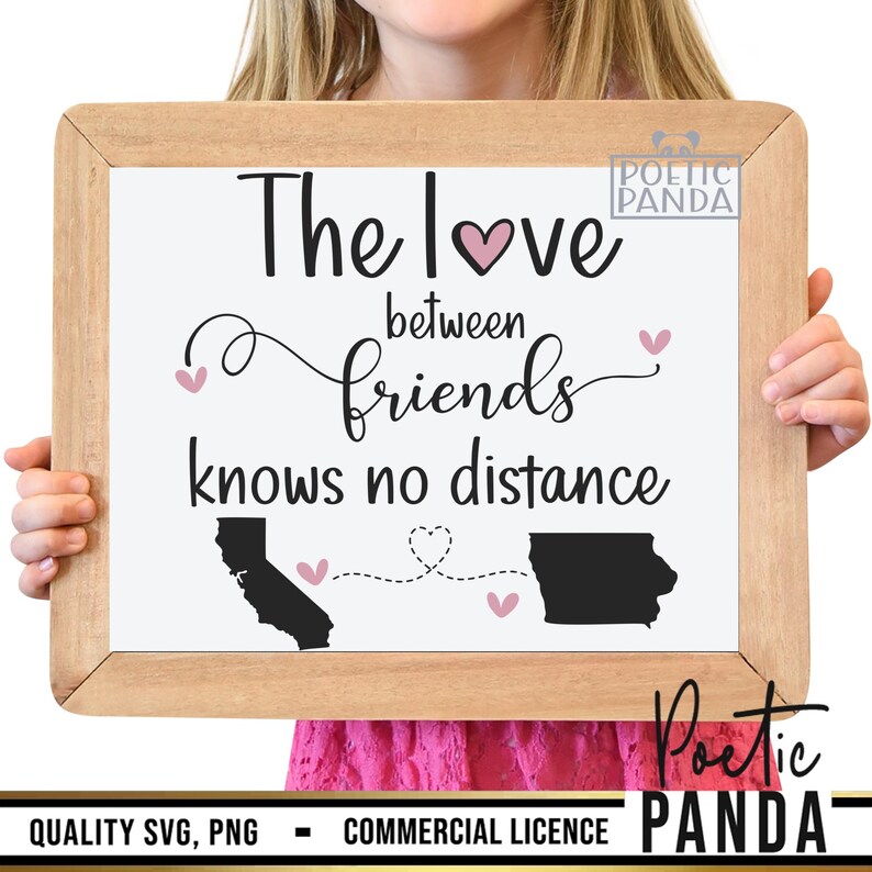 May include: A framed sign with the text "The love between friends knows no distance" with a pink heart and two black outlines of states connected by a dotted line with hearts. The sign is held by a person's hands.