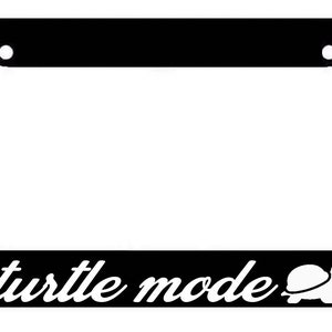 May include: Black license plate frame with white text that reads "turtle mode" and a white silhouette of a turtle.