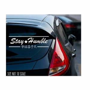 May include: White vinyl decal sticker for a car with the text "Stay Humble" and the Chinese characters for "The road to success is paved with humility".