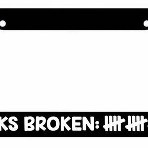 May include: Black license plate frame with white text that reads "NECKS BROKEN:  IIII IIII IIII II".