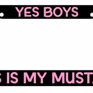 May include: Black license plate frame with pink text that reads "YES BOYS THIS IS MY MUSTANG".