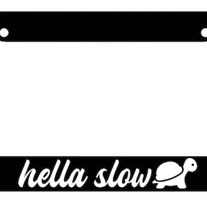 May include: Black license plate frame with white text that reads "hella slow" and a white silhouette of a turtle.