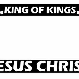 May include: Black license plate frame with white text that reads "KING OF KINGS."  The bottom of the frame has white text that reads "JESUS CHRIST."