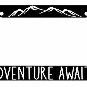May include: Black license plate frame with a white mountain range design and the text "ADVENTURE AWAITS" at the bottom.